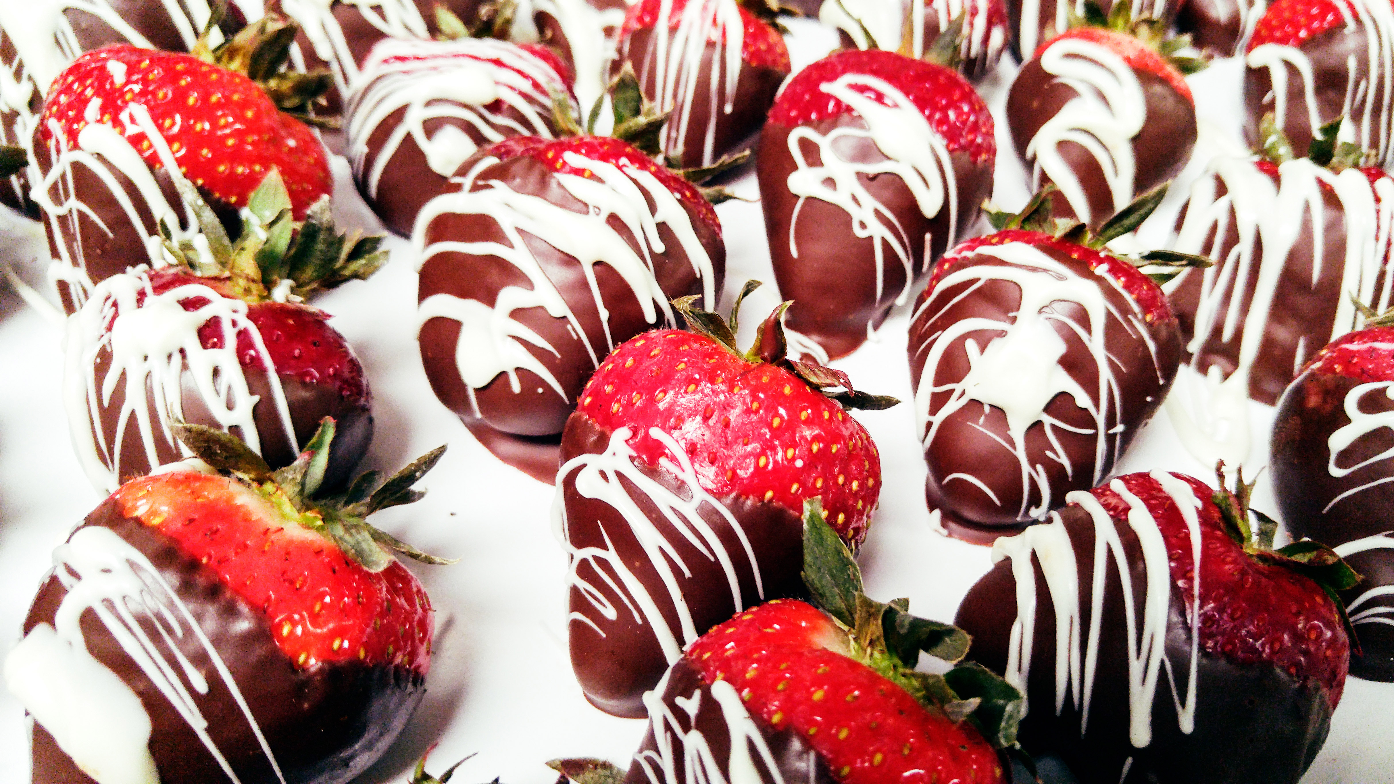 Close up photograph of strawberries drizzled with milk and white chocolate